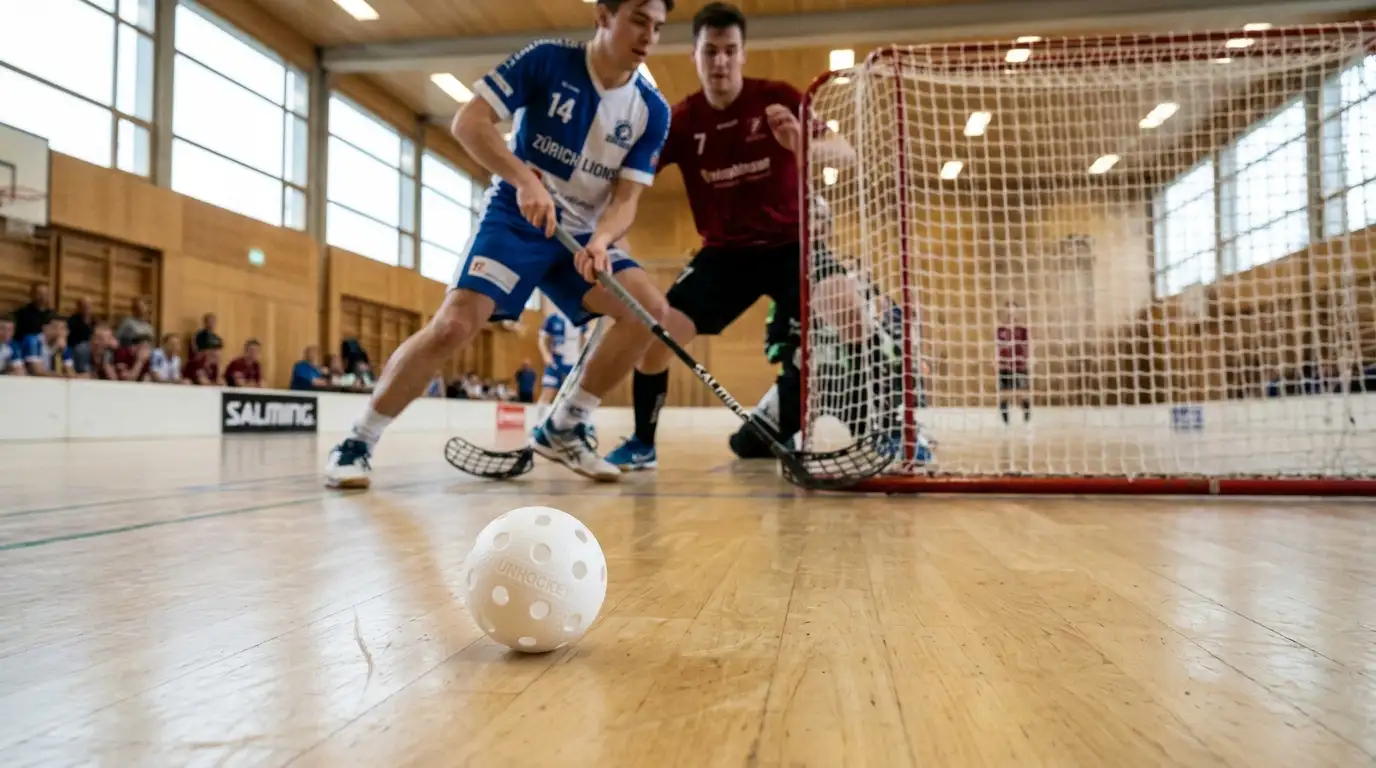 Unihockey-Ball aus weissem Kunststoff mit Löchern auf dem Hallenboden vor dem Tor