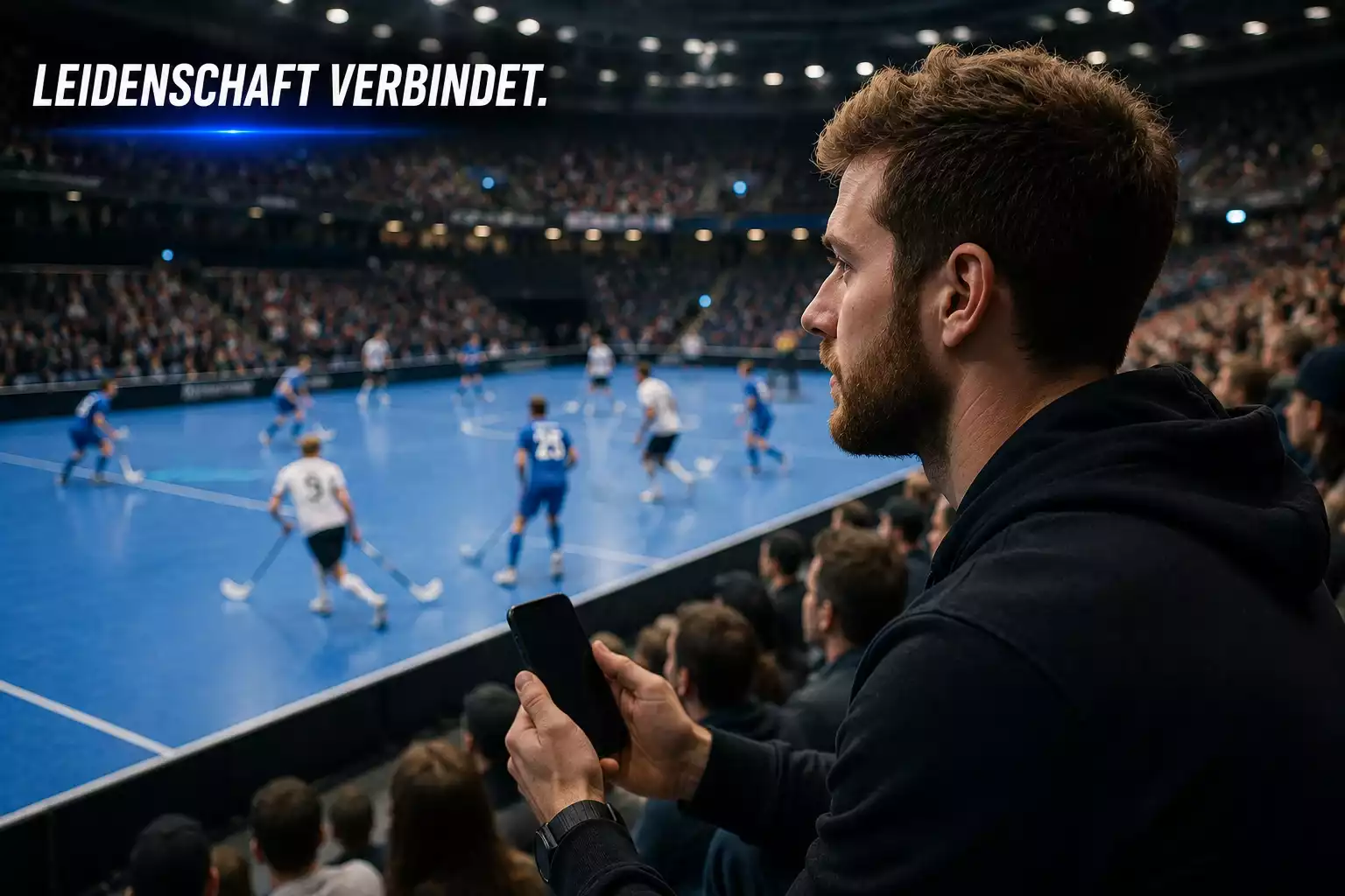 Person tippt am Smartphone auf ein laufendes Unihockey-Spiel in der Halle im Hintergrund