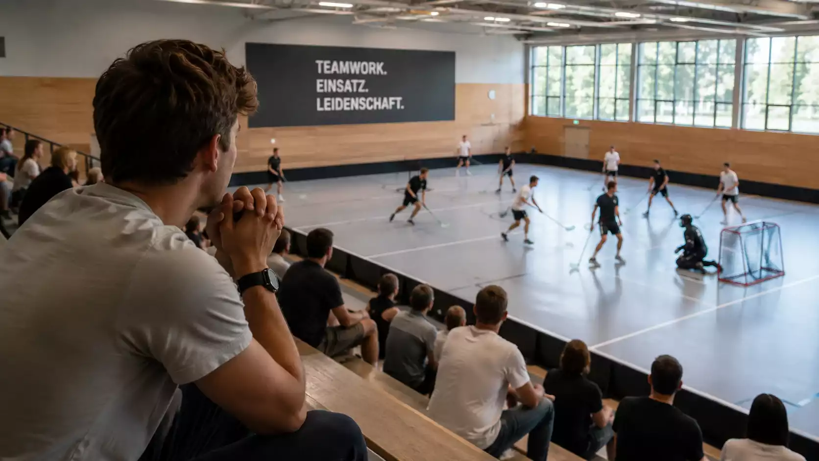 Zuschauer auf der Tribüne verfolgt ein laufendes Unihockey-Spiel