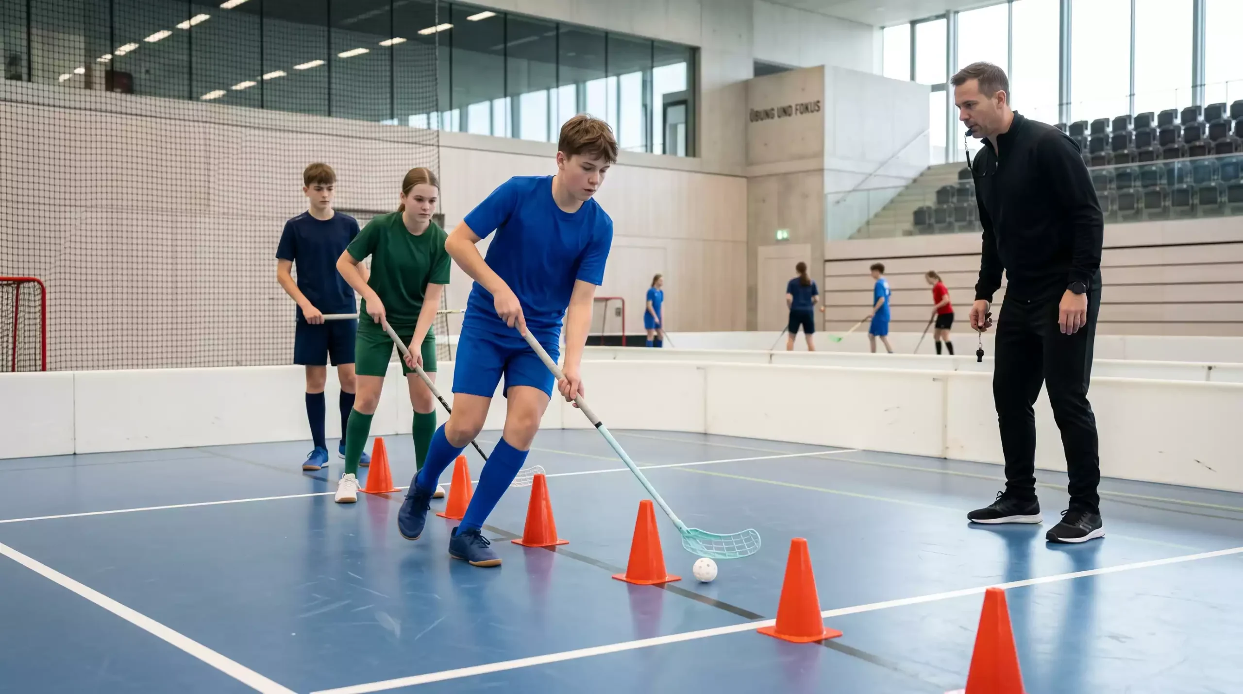 Junge Unihockey-Spieler üben mit Schläger und Ball in der Halle