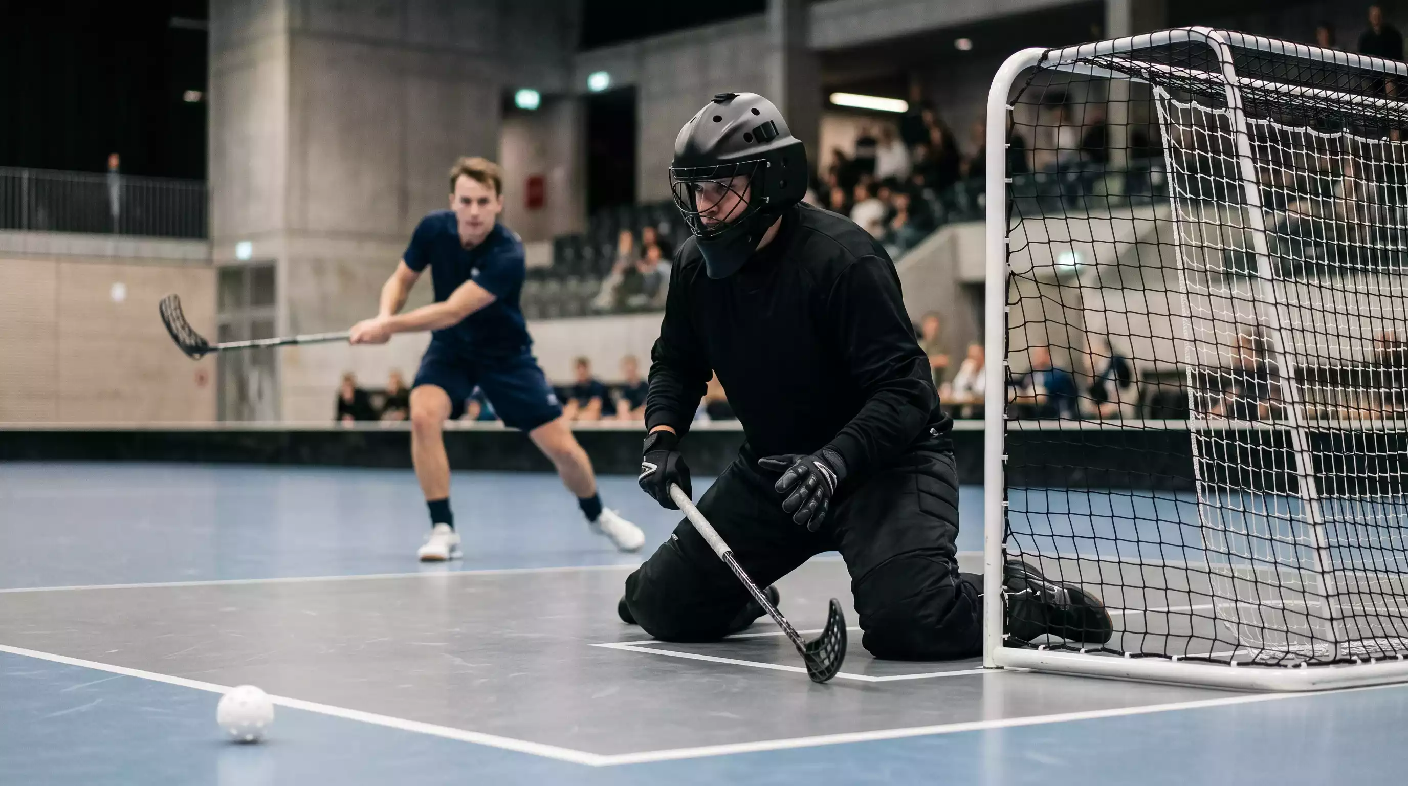Unihockey-Torhüter in Aktion vor dem Tor während einer intensiven Druckphase